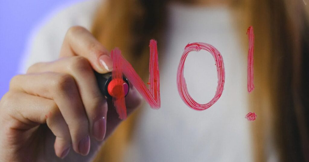 「no」の文字と書く女性