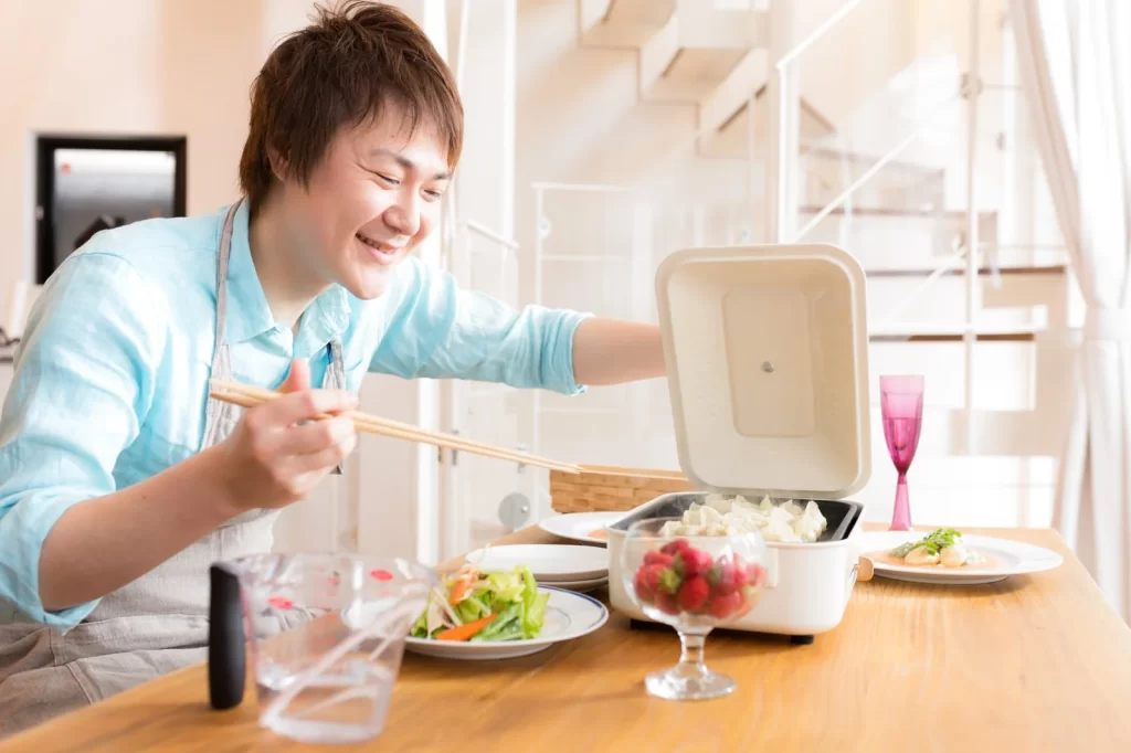 ホットプレートで餃子を焼いている男の人