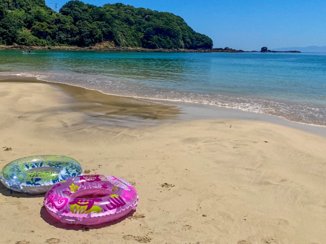 浜辺に置かれたピンクと青の浮き輪