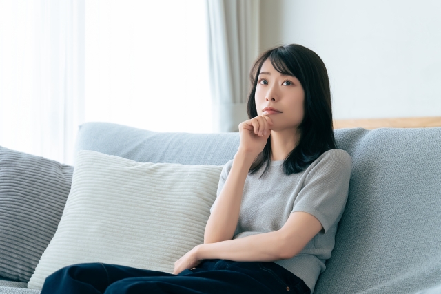 ソファに座って考え事をする女性