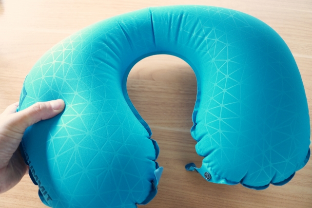 水色のネックピローを持っている手元