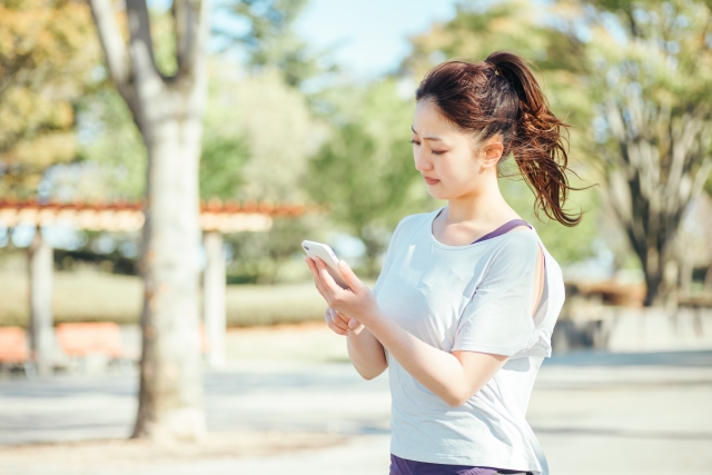 公園でスマホを操作している女性