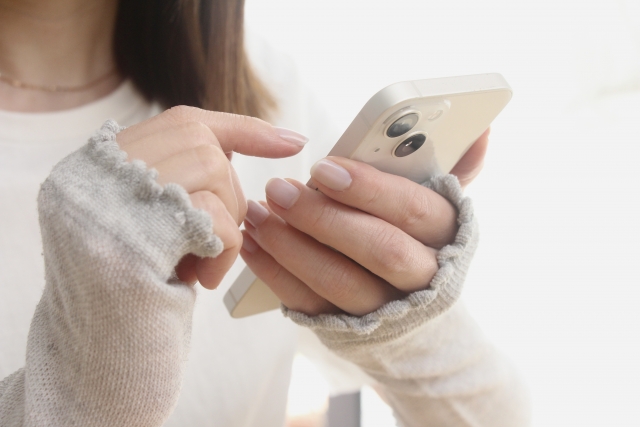 アームカバーをしてスマートフォンを触っている女性
