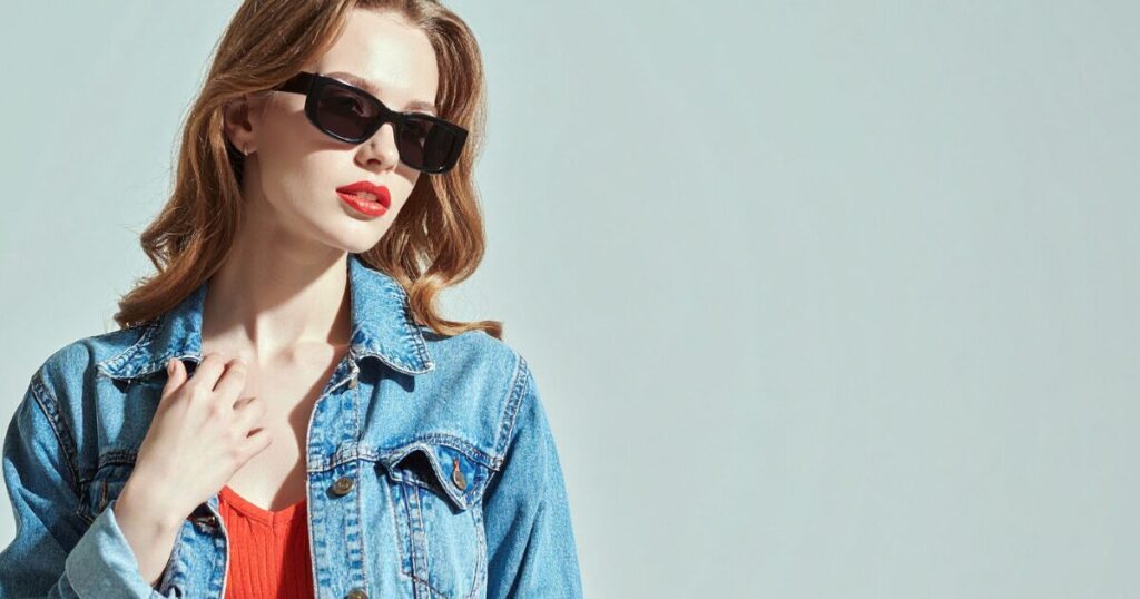 赤いトップスにブルーのデニムジャケットを羽織ったサングラス姿の女性
