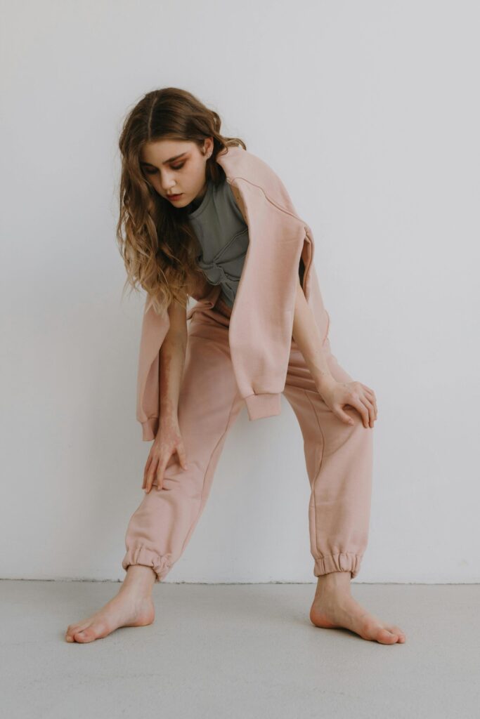 くすみピンクのスウェットパンツを穿いてストレッチしている女性
