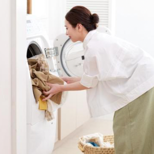 女性が洗濯機に洋服を入れている
