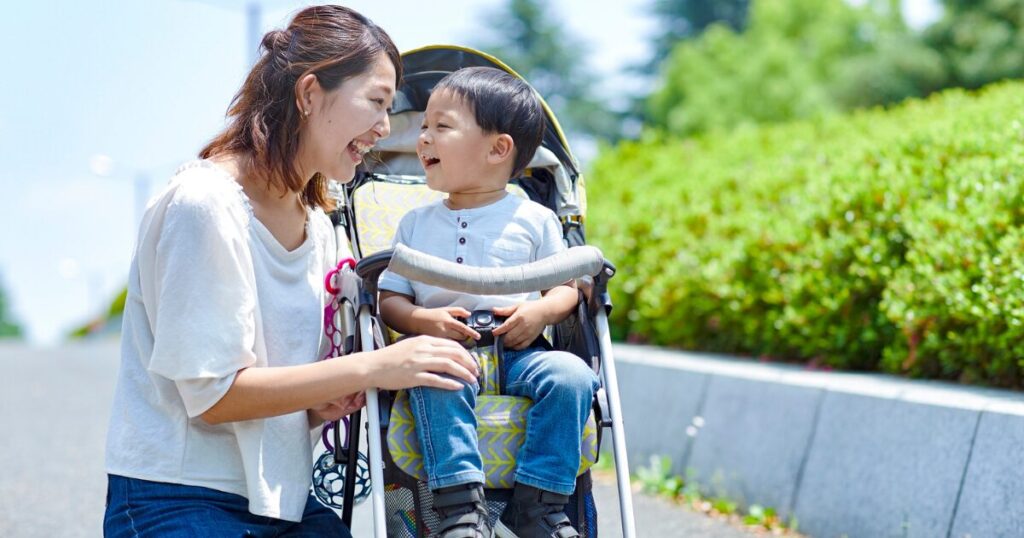 笑顔で見つめ合っているお母さんとベビーカーに乗った子ども