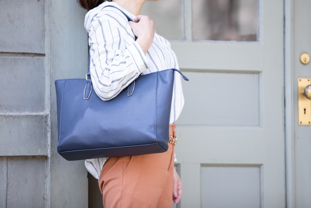 ネイビーのトートバッグを肩にかけている女性