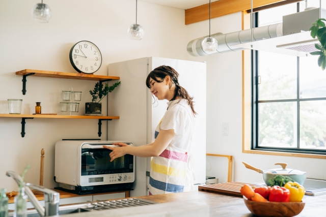 キッチンに立つオーブンを使っている女性