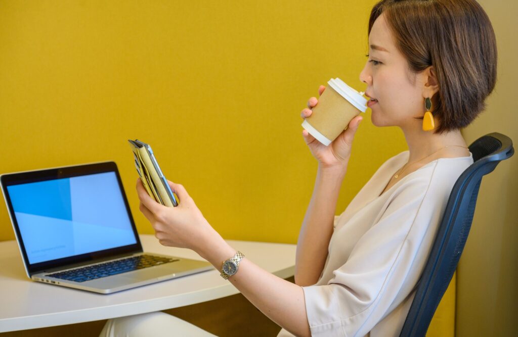 コーヒーを飲みながらスマホを見る女性
