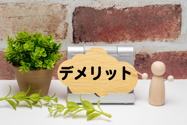 レンガの背景前にデメリットの文字
