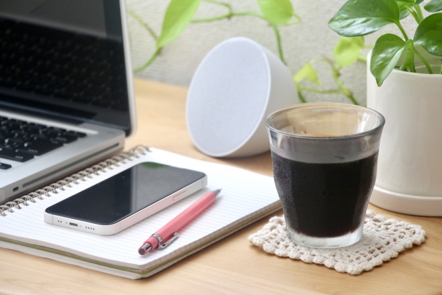 スマホやスピーカー、アイスコーヒーなどが置かれている机の上