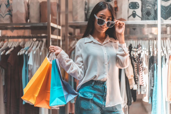 服屋の店頭に立つ紙袋を持った女性