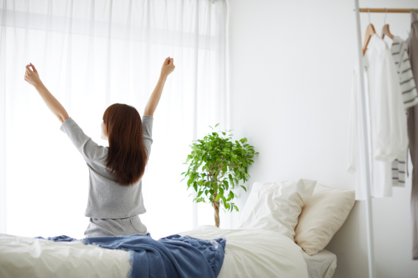 寝室で伸びをする女性