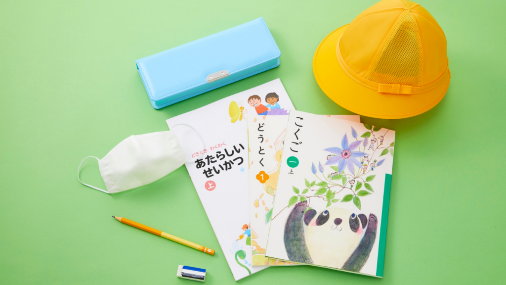 黄緑の背景に筆箱、黄色い帽子、マスク、教科書、消しゴム、鉛筆