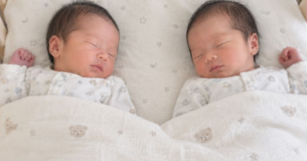 1台のベッドに一緒に寝ている双子の赤ちゃん